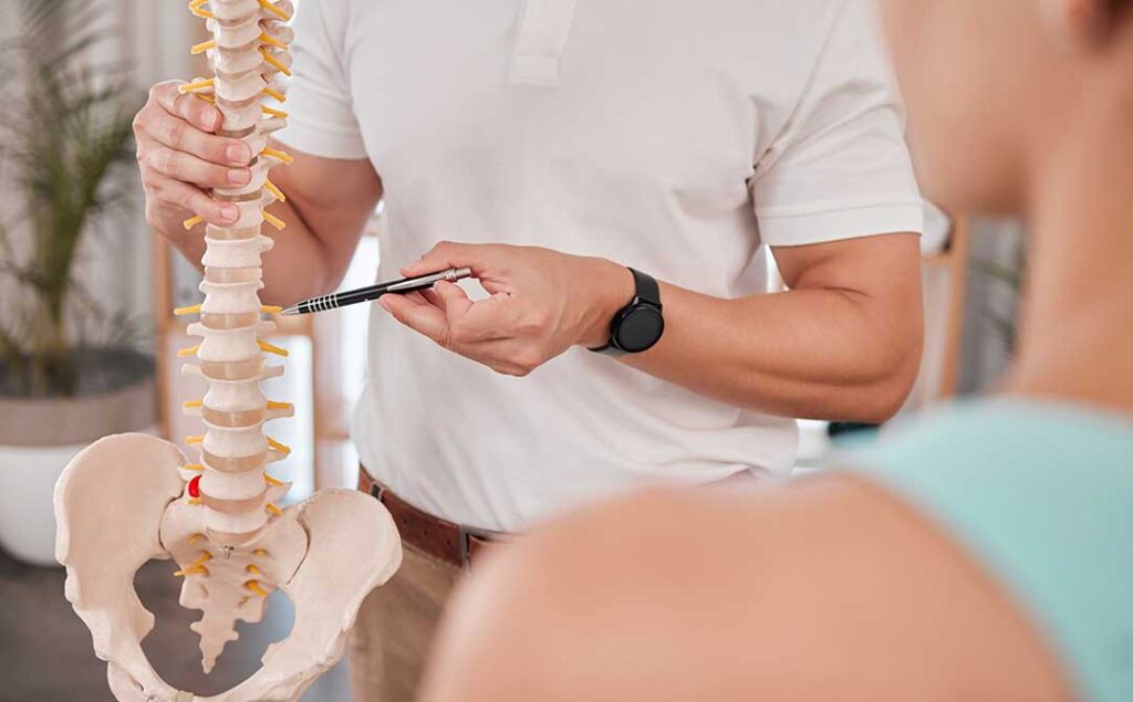A chiropractor performing a spinal adjustment on a patient lying face down on a treatment table.